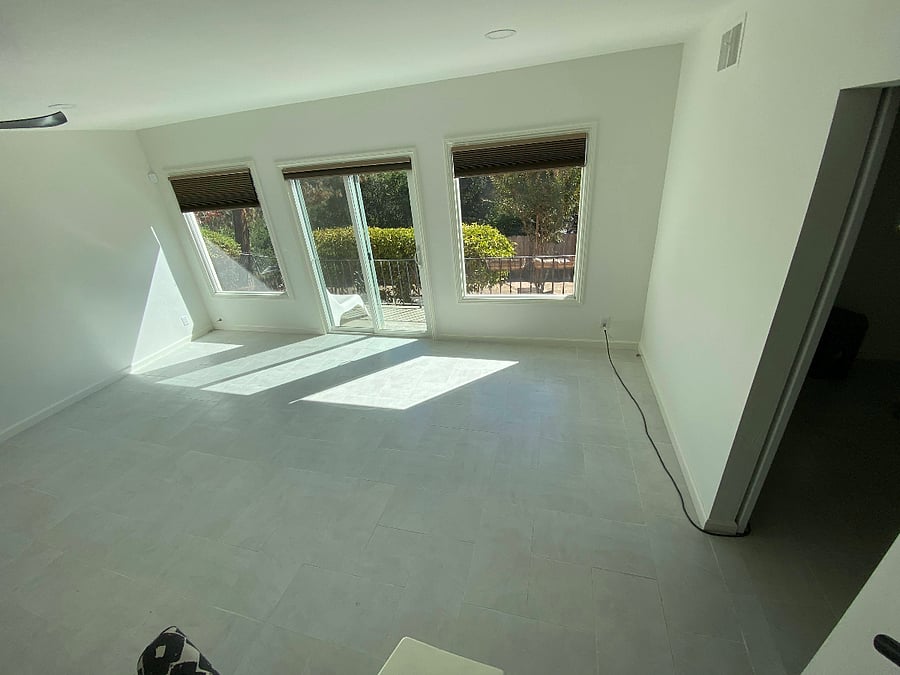 living room view, with screened back sliding glass door and partial kitchenette view (on right) from connecting stairway.