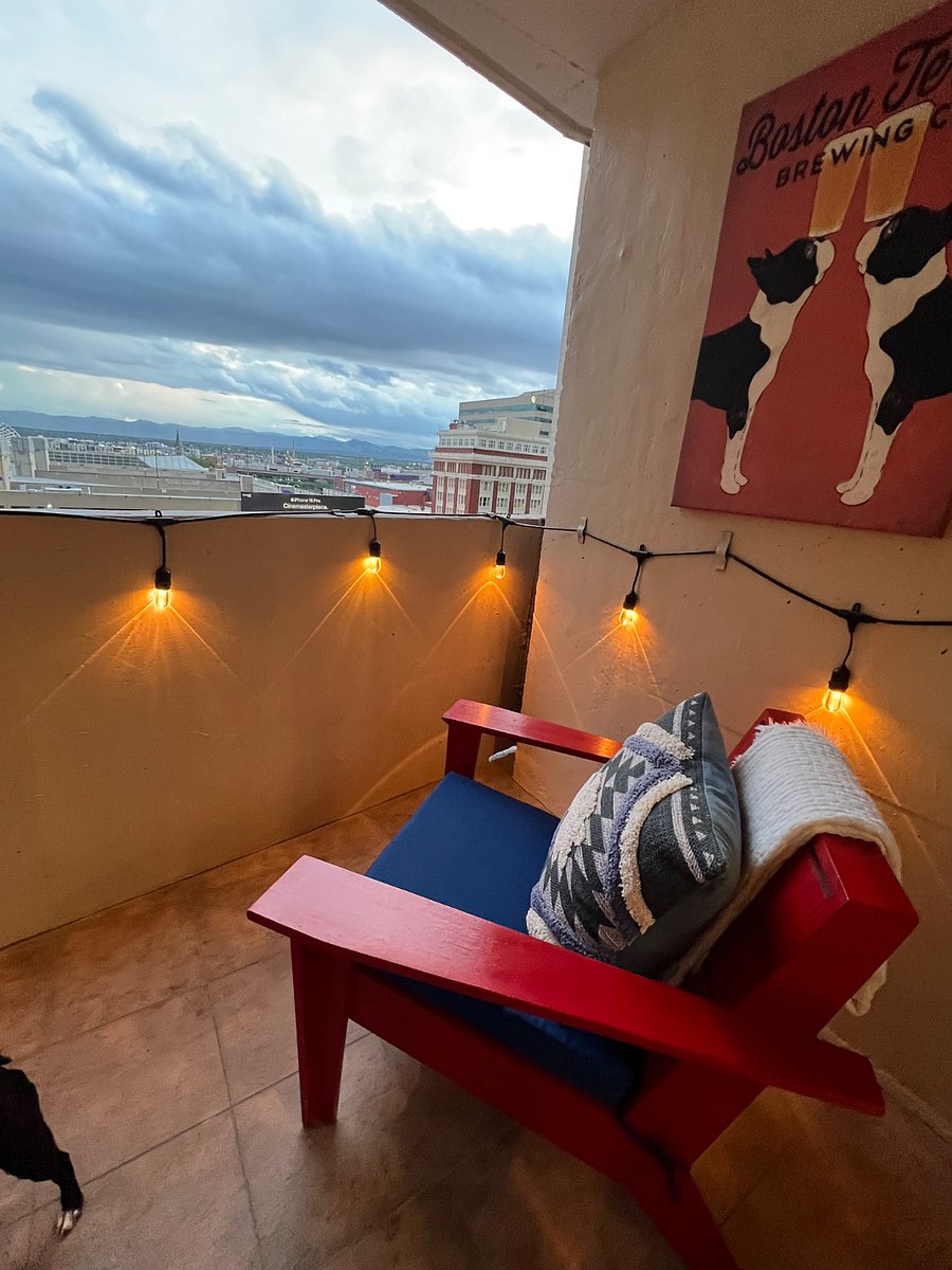 Balcony with festive lighting, modern adirondack chairs with fresh paint and a planter