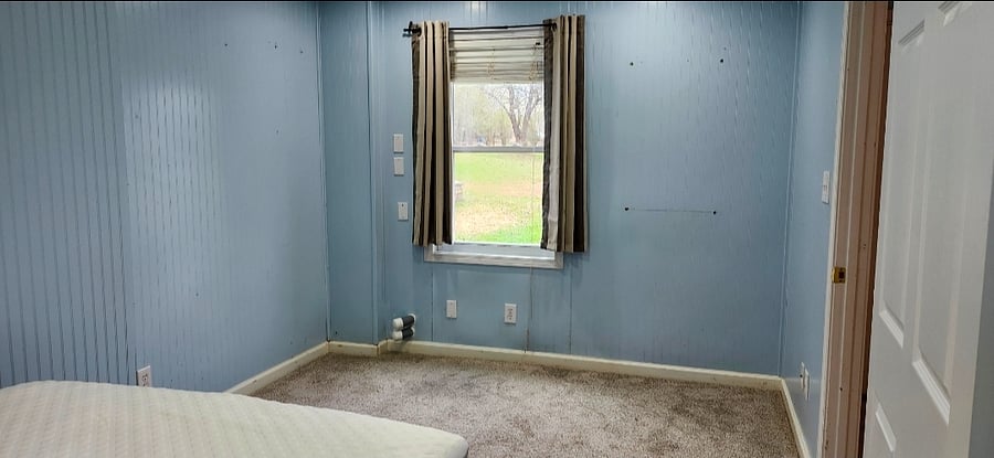 Bedroom features a window overlooking a peaceful rural setting, bringing in natural light and a relaxing country view.