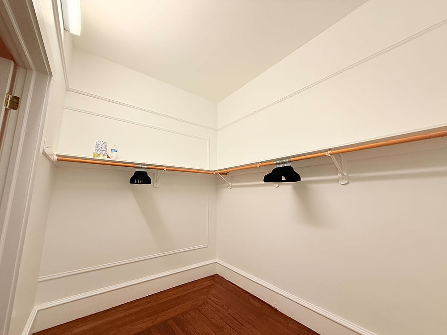 An alternate view of the spacious walk-in closet, showcasing the wrap-around shelving and clothing rods with plenty of room for storage.