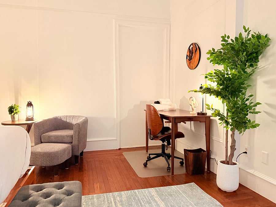Detailed view of the bedroom's dedicated workspace, featuring a stylish wooden desk, rolling office chair, and a cozy armchair seating nook.