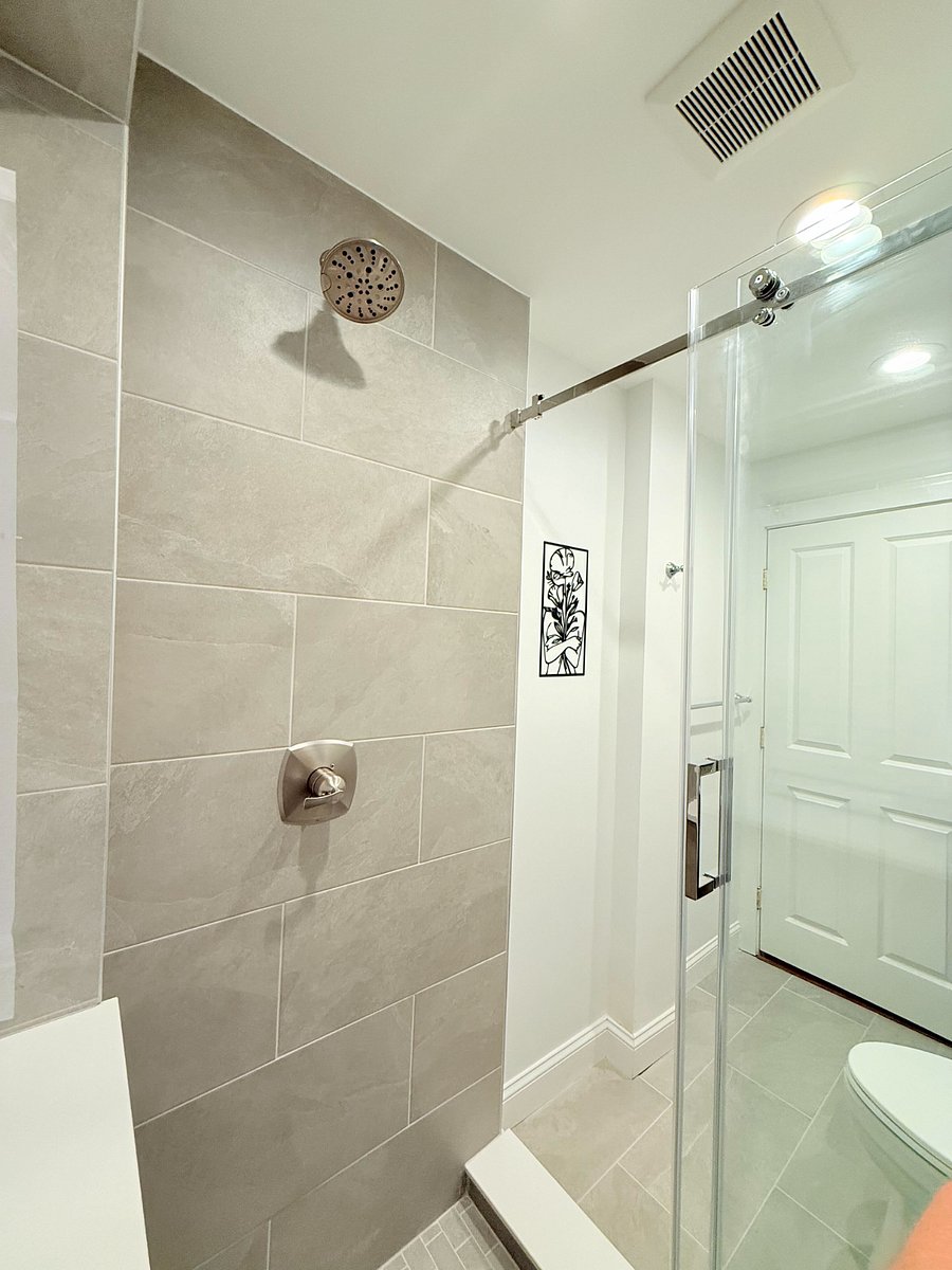 modern shared bathroom featuring a glass-enclosed walk-in shower with contemporary large-format tiling