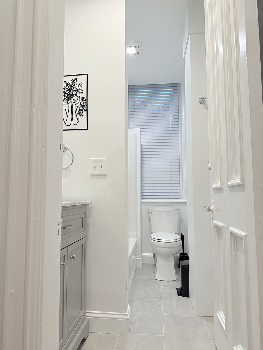 A view of the shared bathroom looking in from the doorway, highlighting the light-colored walls, vanity, and modern bathroom fixtures