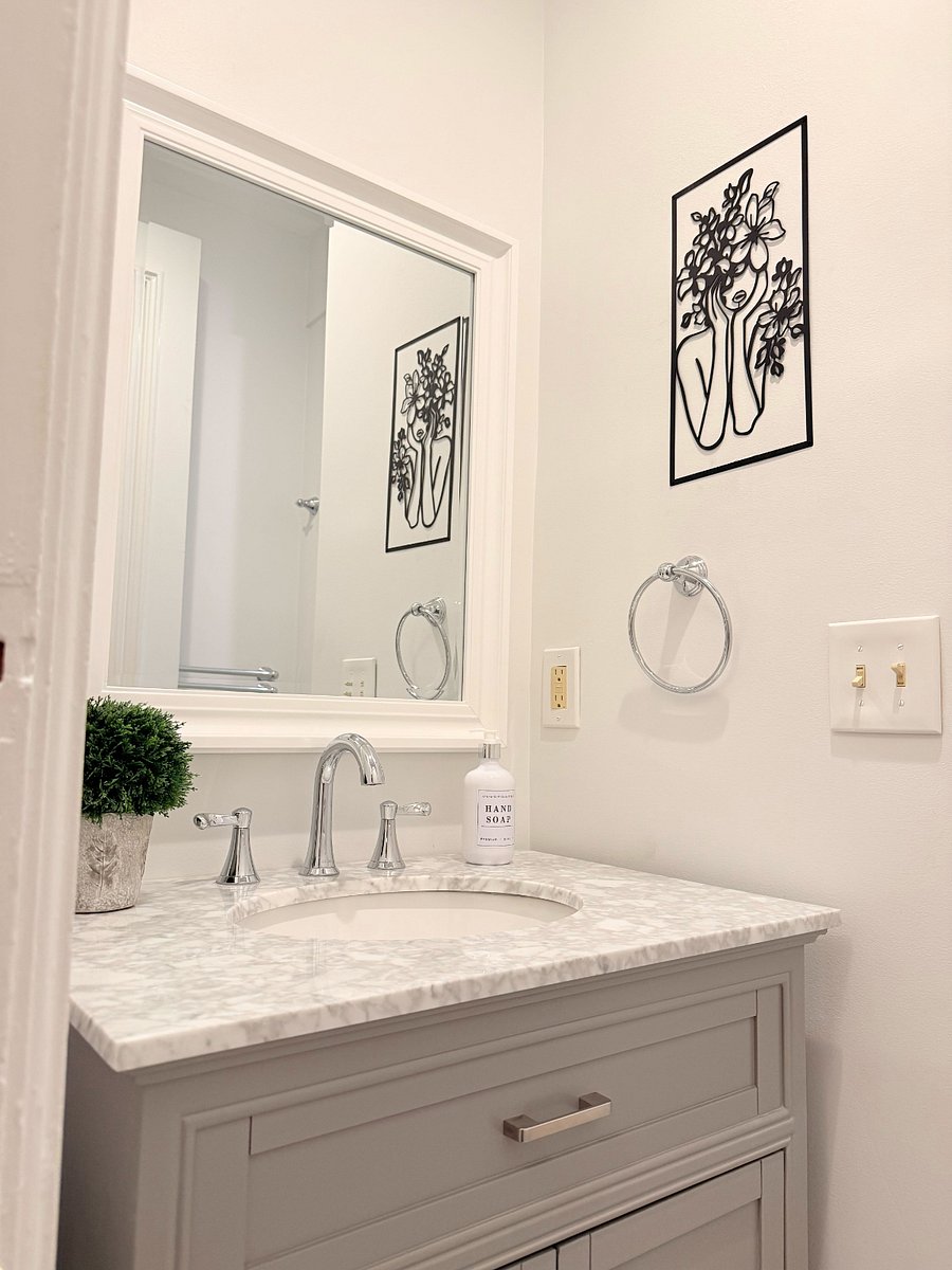 Close-up of the shared bathroom vanity featuring a marble countertop, large mirror, and elegant wall art.