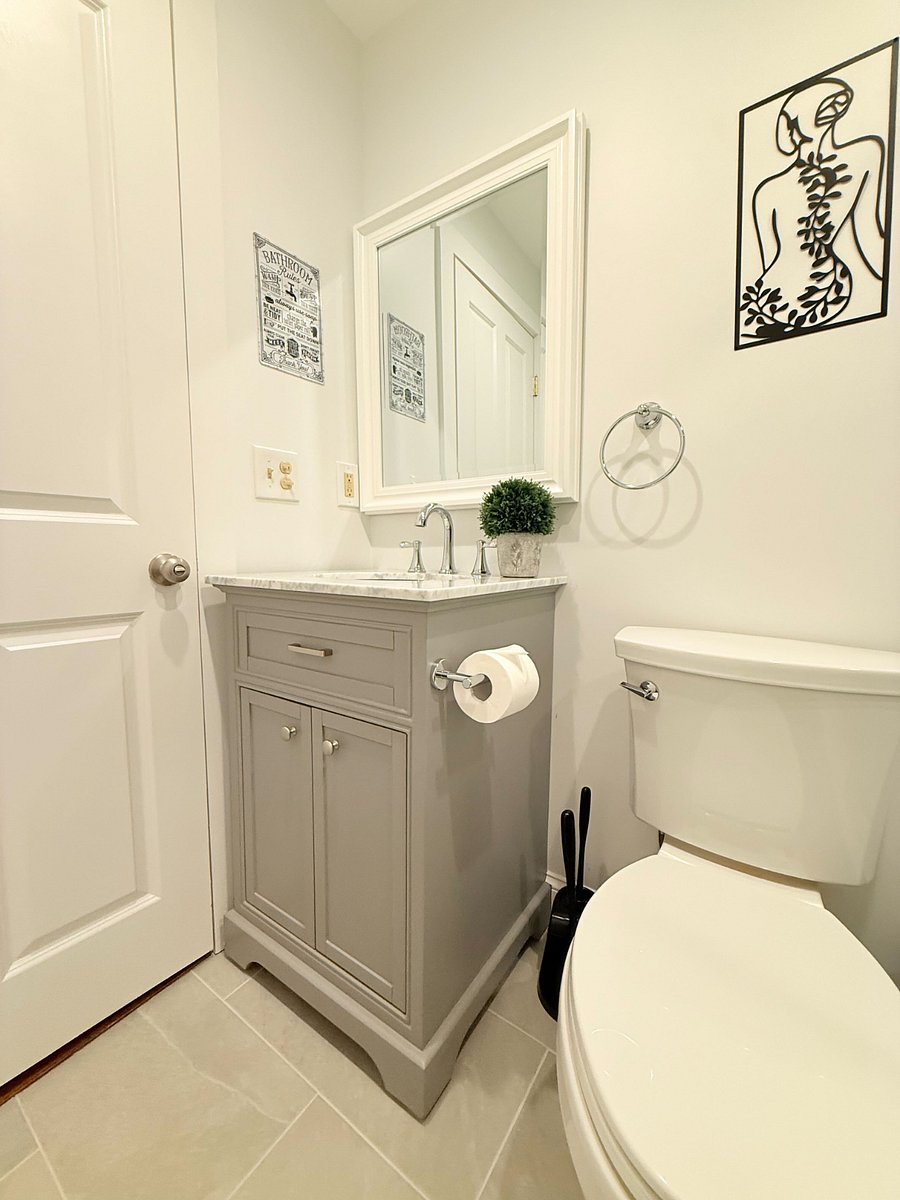 Shared bathroom space with a grey vanity, white mirror, and decorative wall art