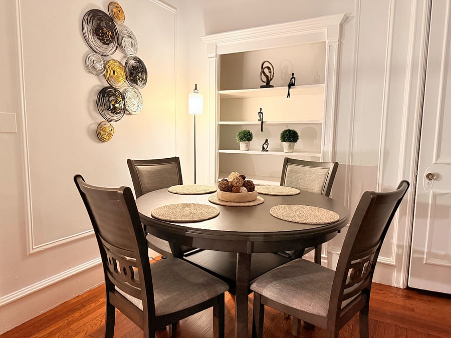 A stylish dining nook with a round table, elegant wall accents, and built-in shelving