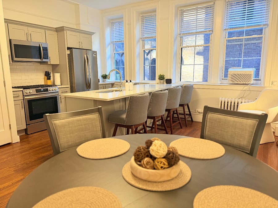 View from the dining table showcasing the open-concept layout, highlighting the modern kitchen island with bar seating and stainless steel appliances
