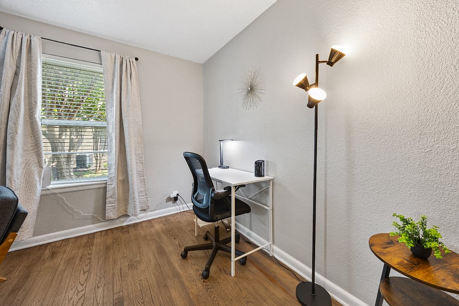 Working space with desk, office chair, smart lamp, and cord organizer.