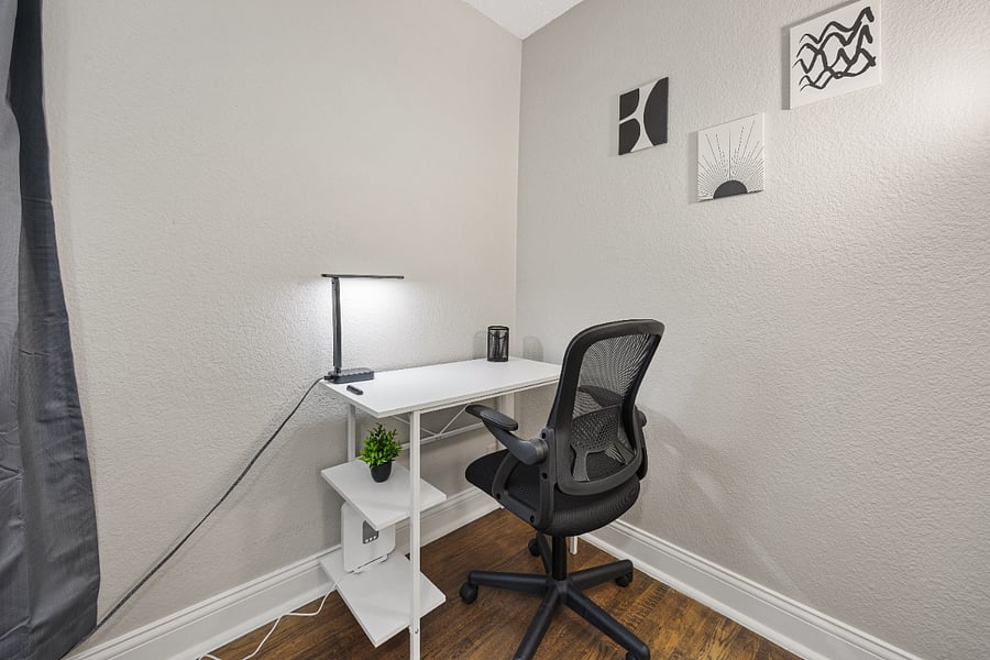 Working space with desk, office chair, smart lamp, and cord organizer.