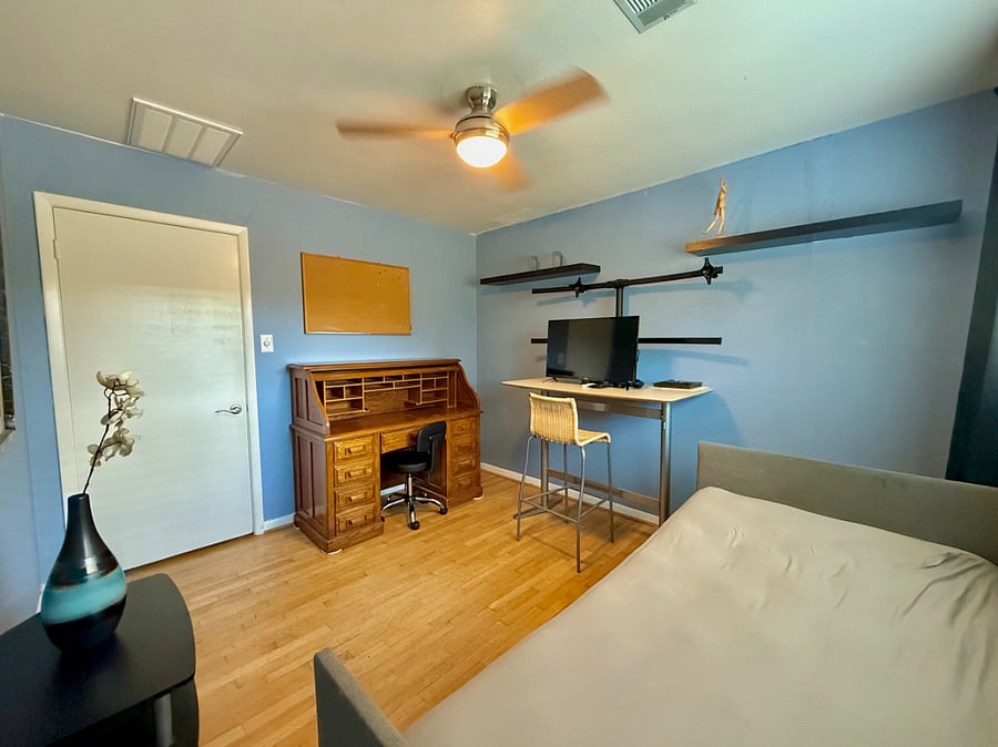 office, furnished with two desks, a monitor, and sofa bed