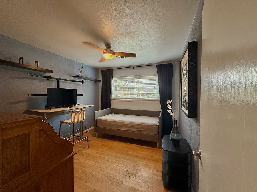 office, furnished with two desks, a monitor, and sofa bed