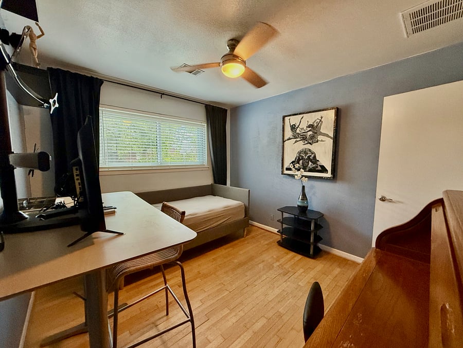 office, furnished with two desks, a monitor, and sofa bed