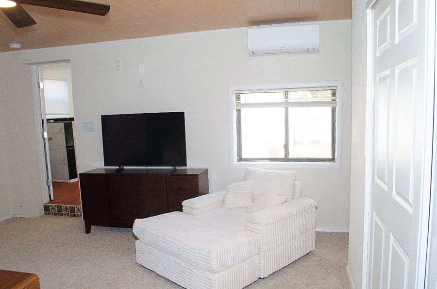 Living area with lounge chair and Samsung smart TV. Mini split for head and ac