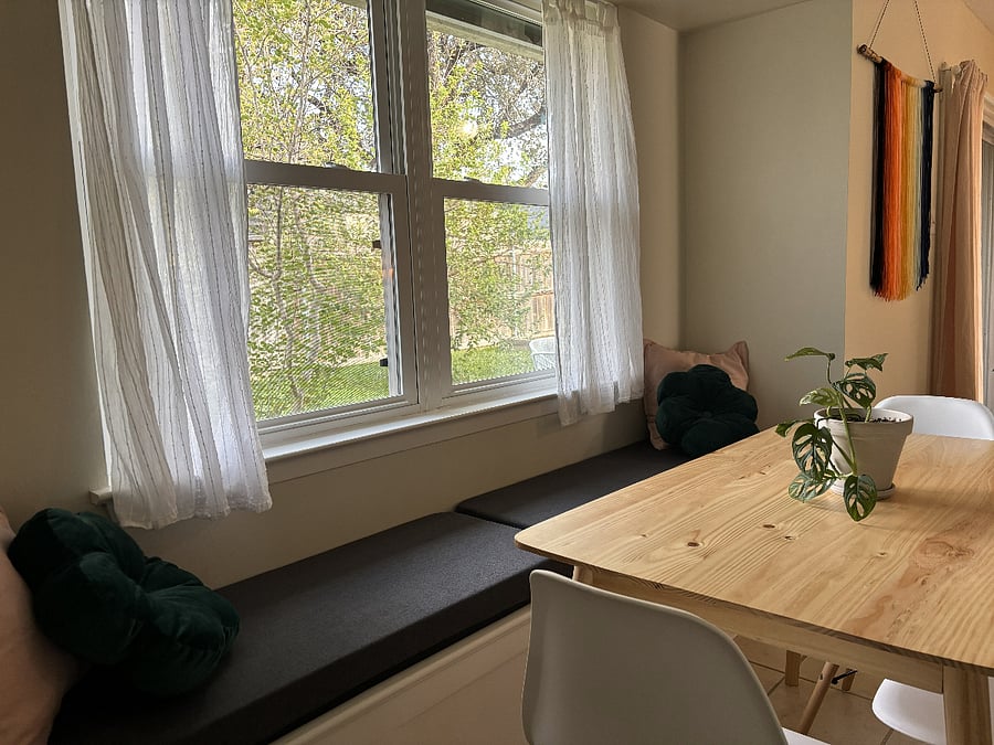 Dining bench seat with light-filtering sheer curtains give the space a calm, comfortably enclosed atmosphere.