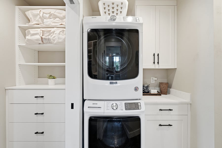 Laundry area with storage and pull out hamper drawer.