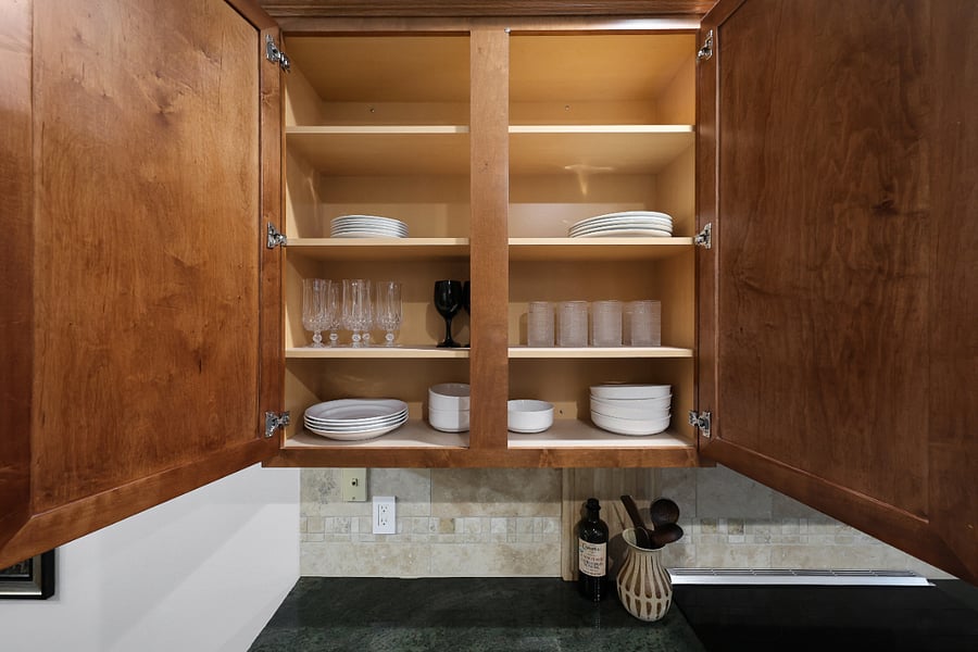 Kitchen cupboards are stocked with plates, cups, and tableware.
