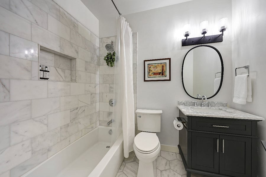 Guest bathroom features marble finishes and a full bathtub.
