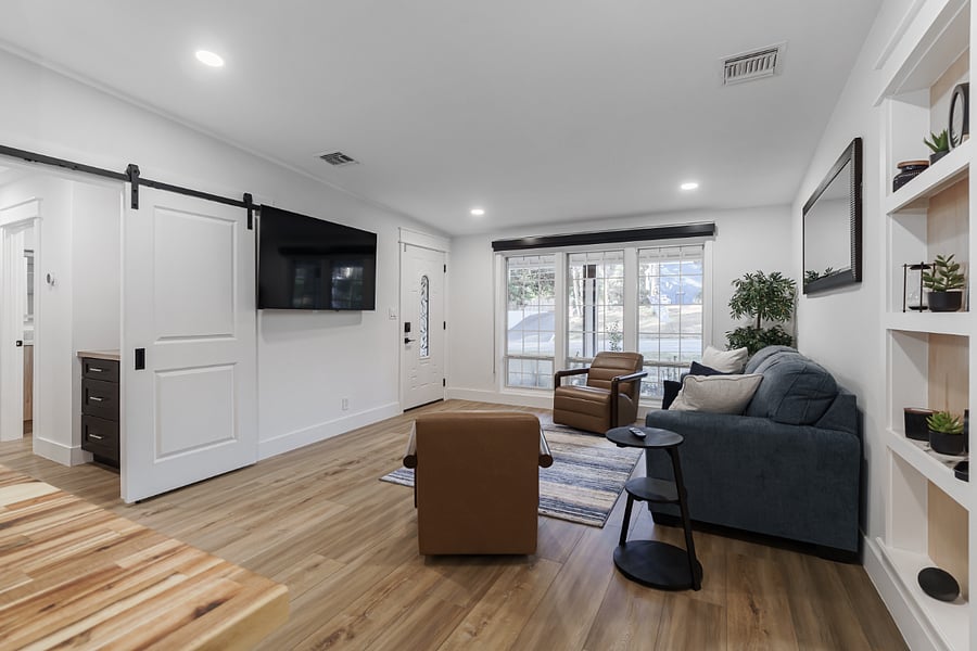 Inviting open-concept living room with large windows, warm wood floors, and stylish seating. Cozy yet modern with natural light, built-in shelving, with ease to voice activate "Alexa" for music  perfect for relaxing or entertaining.