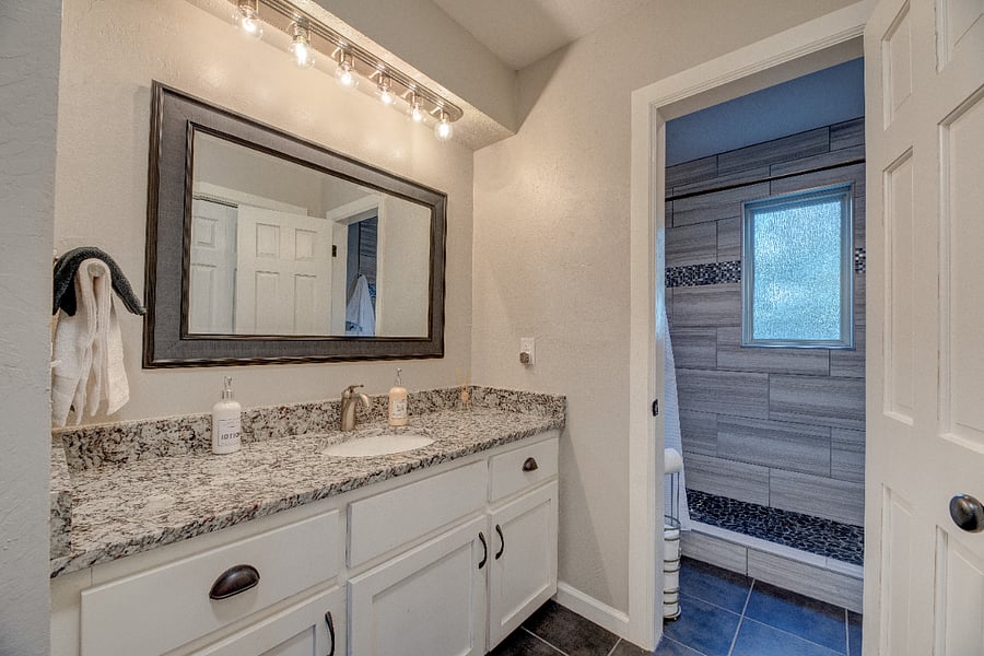 Bright bathroom with granite counters and plenty of storage.