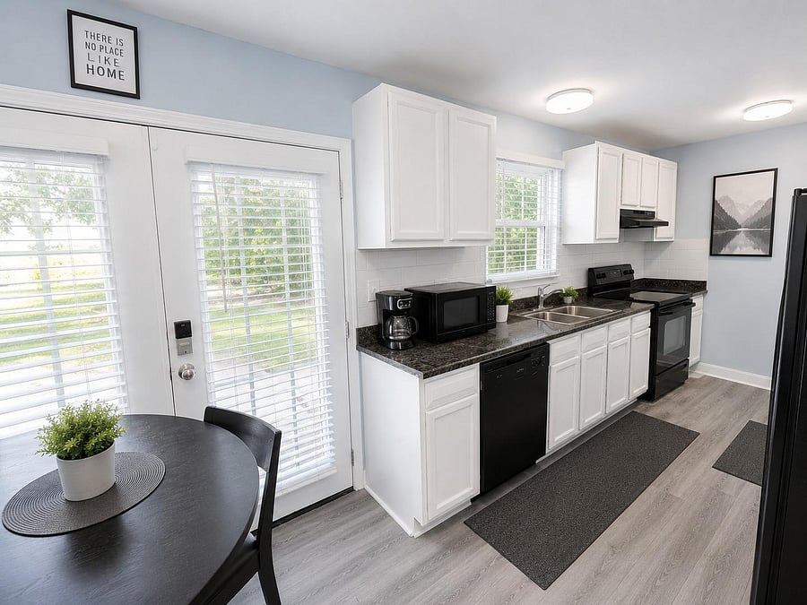 Eat-in kitchen with white cabinetry, ample counter space, double sink, dishwasher, and electric range plus patio access.