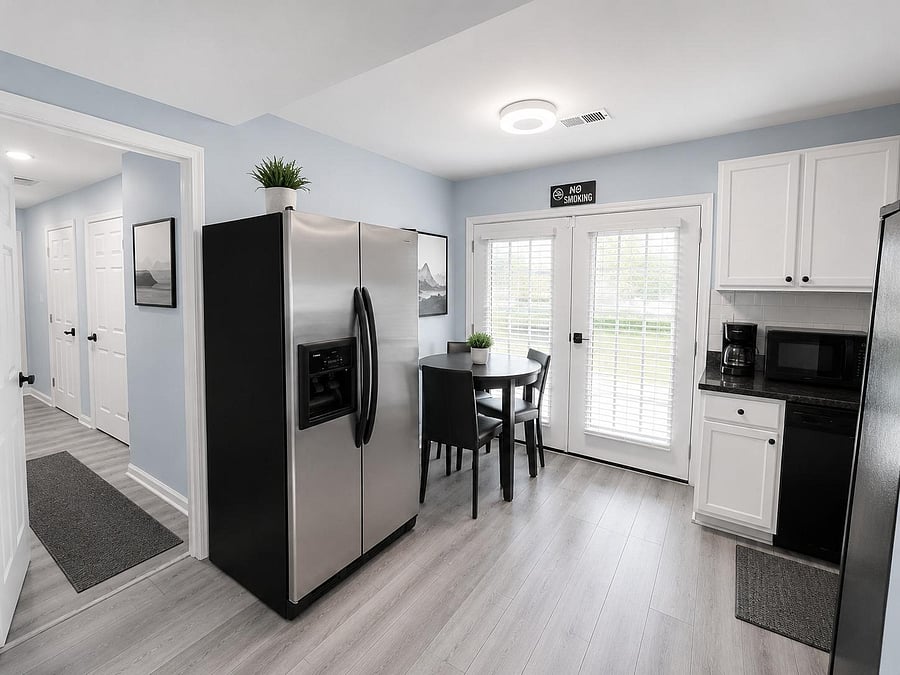 Eat-in kitchen features stainless side-by-side fridge, ample cabinetry, and a dining nook beside glass patio doors.