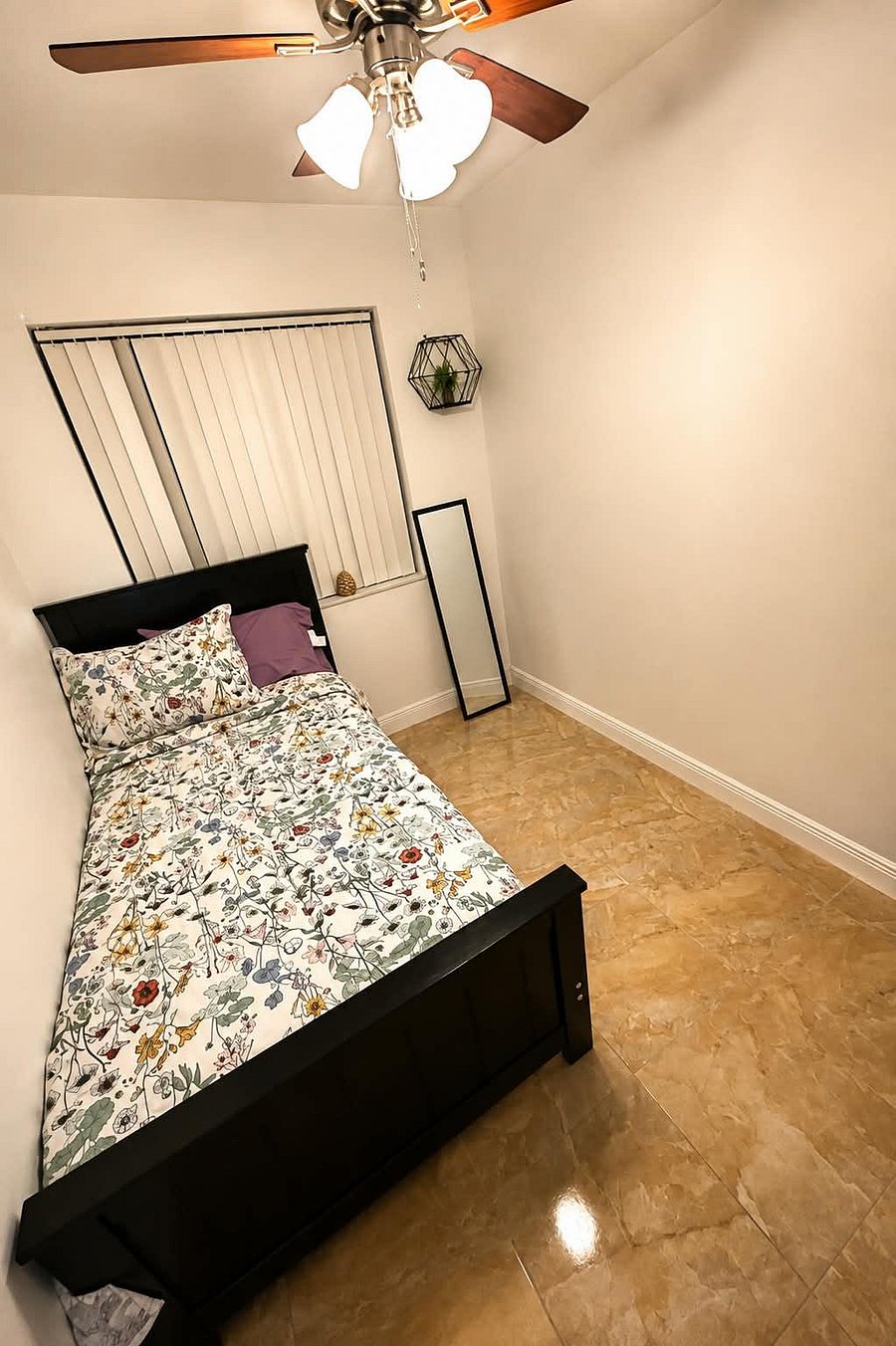 Private bedroom with tile flooring, ceiling fan light, and a window with vertical blinds--ideal for simple, low-maintenance li