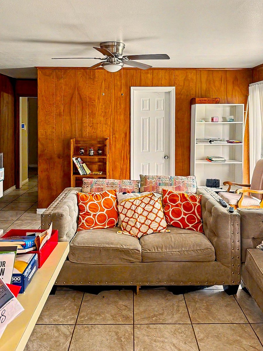 Common living area with ceiling fan, tile flooring, and comfortable seating, plus shelving for books and shared storage.