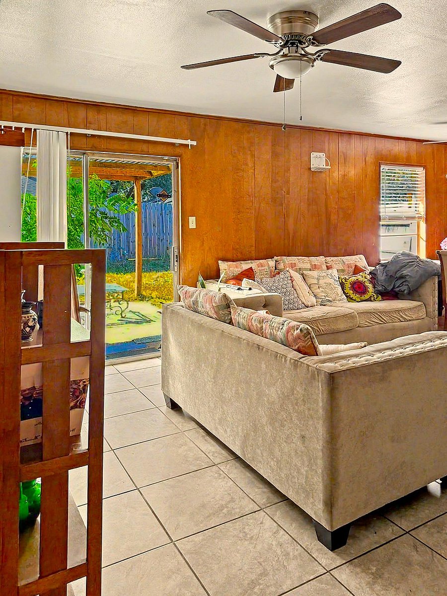 Living room with tile flooring, ceiling fan, and a comfortable seating area with sliding doors to the backyard patio.