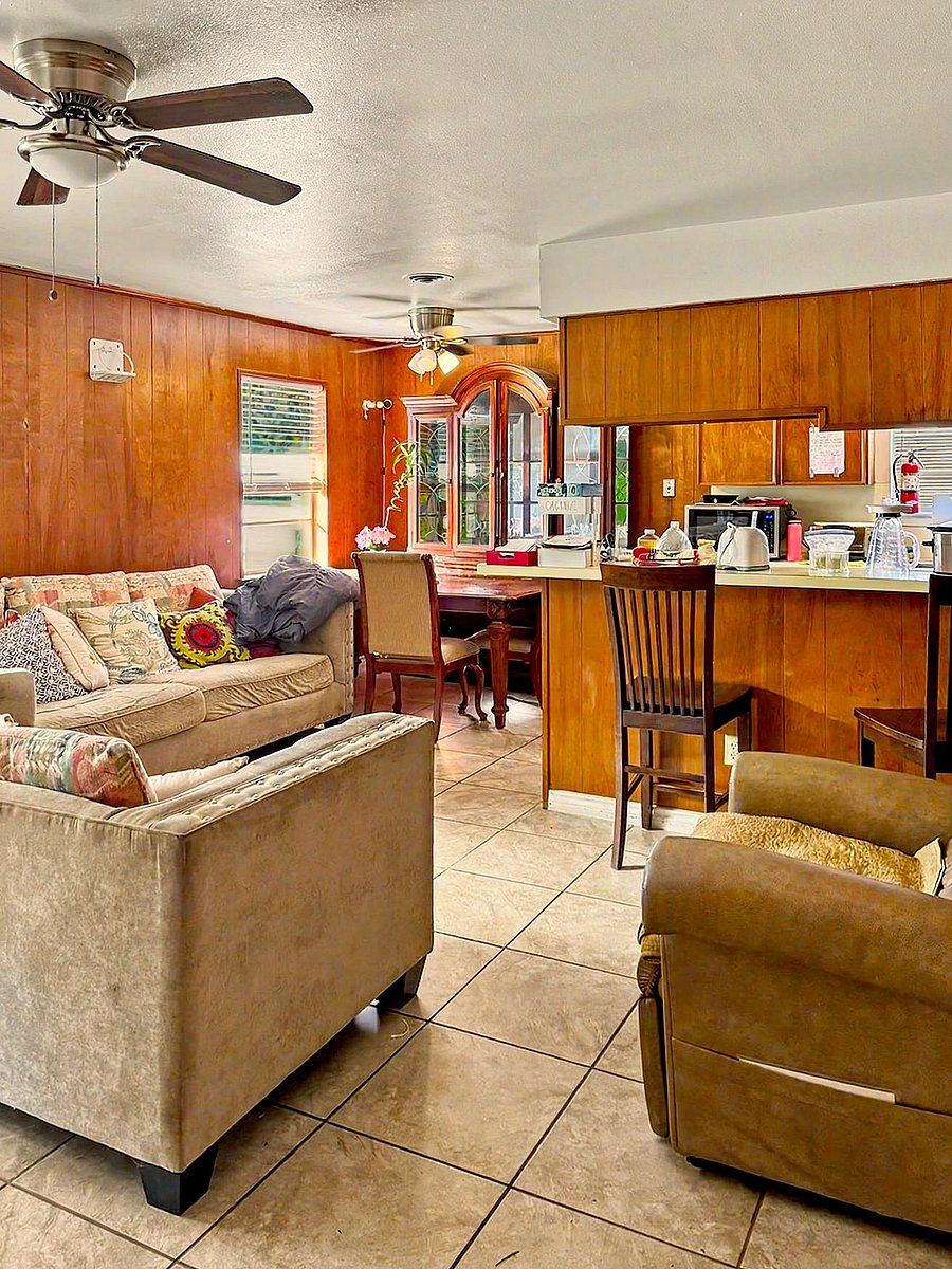 Open living area with tile flooring, ceiling fans, and an adjacent breakfast bar that connects to the kitchen.
