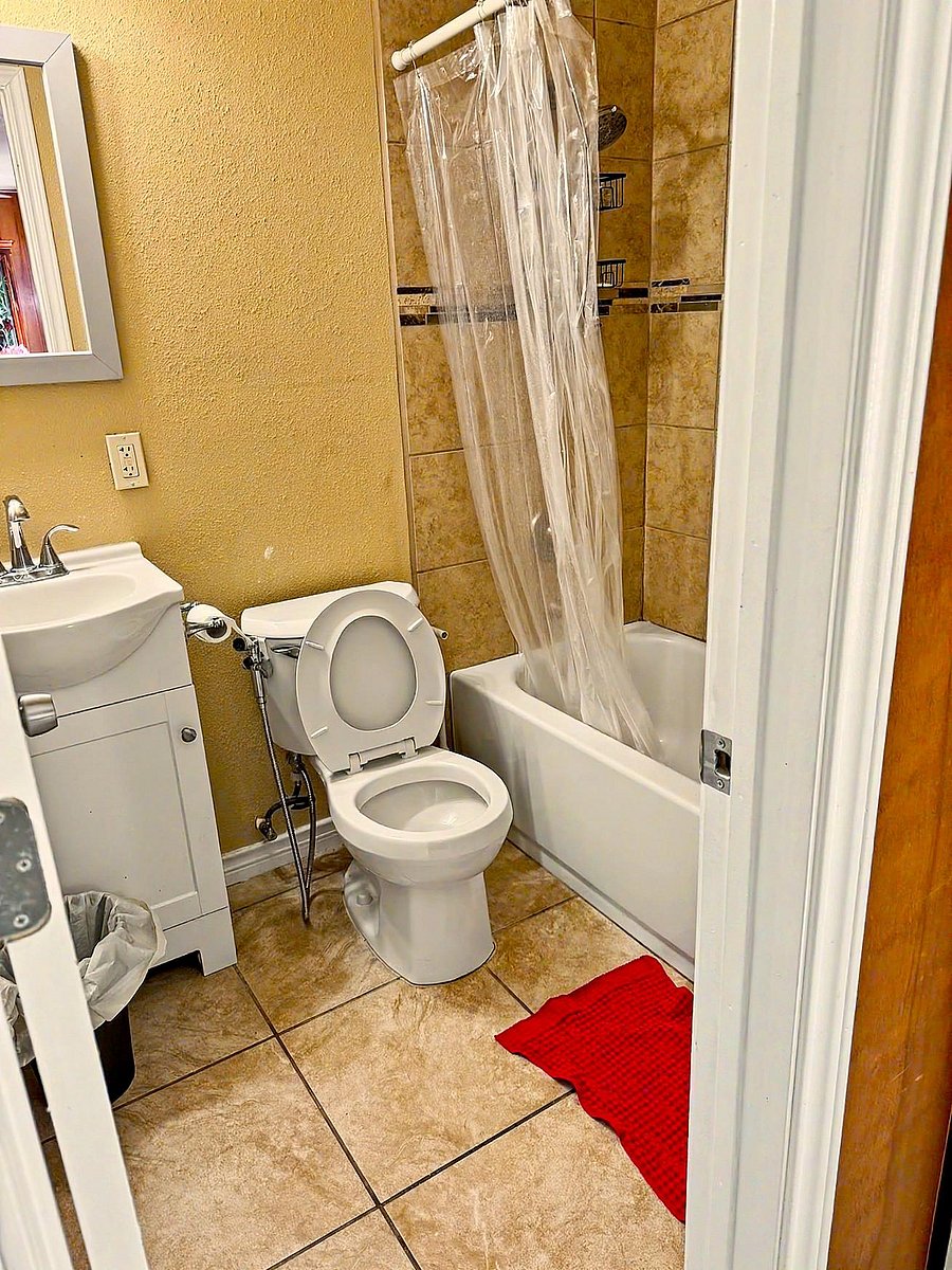 Full bathroom with a tiled tub/shower combo, vanity with mirror, and easy-clean tile flooring for everyday convenience.
