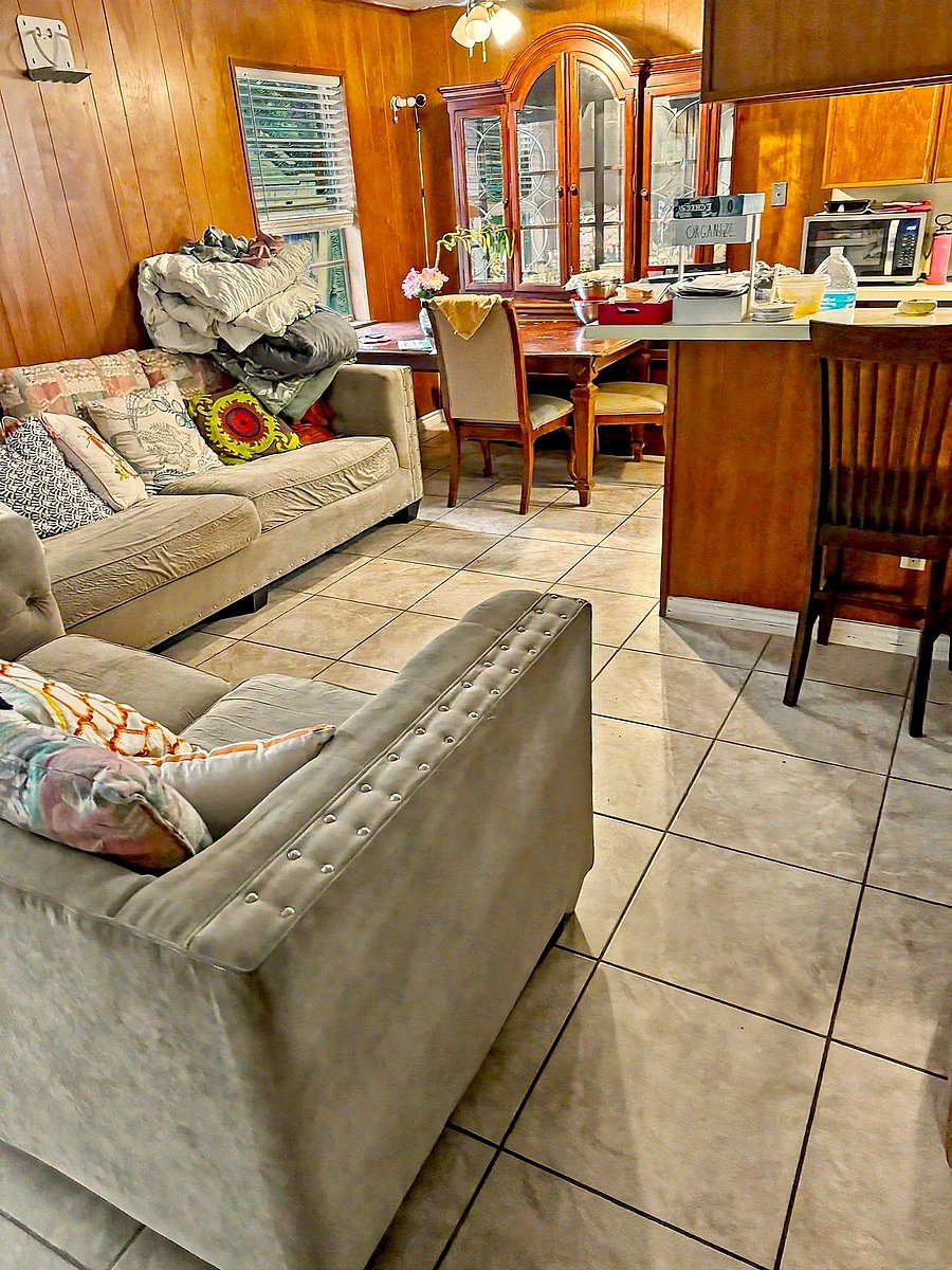 Open living area with tile floors, a comfortable seating zone, and a dining nook beside the kitchen breakfast bar.