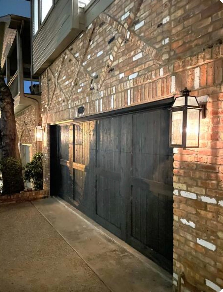 Exterior with a cedar garage door and gas lamps.