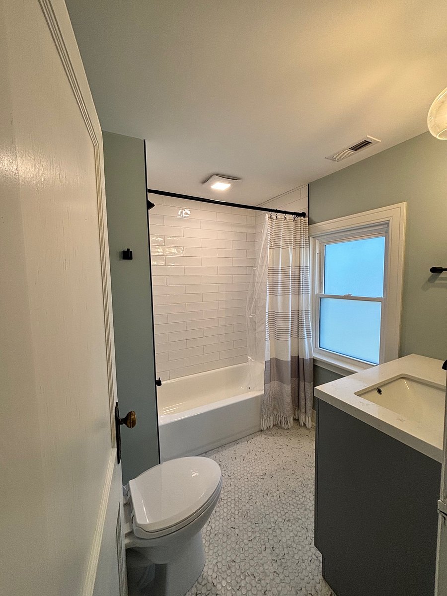 Fresh, renovated bathroom with tub and tile surround. 