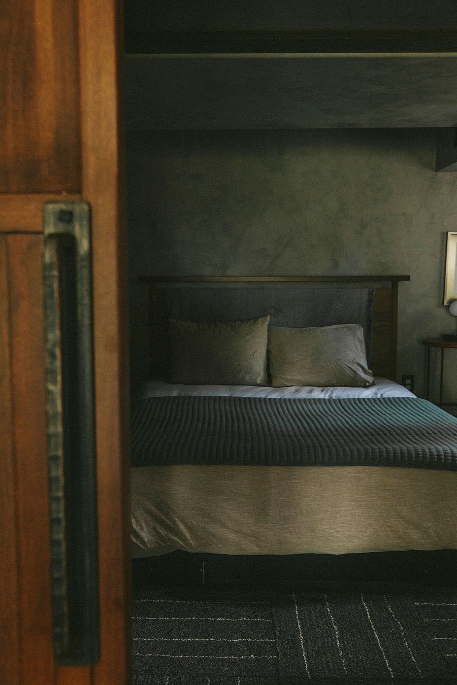 moody view of cozy "best sleep ever!" bedroom area that has room darkening shades over window.