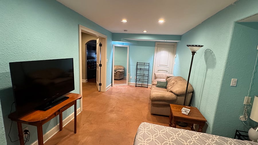 Large Private Bedroom with Smart TV,  a full-sized bed, floor-to-ceiling mirror and sitting area. 