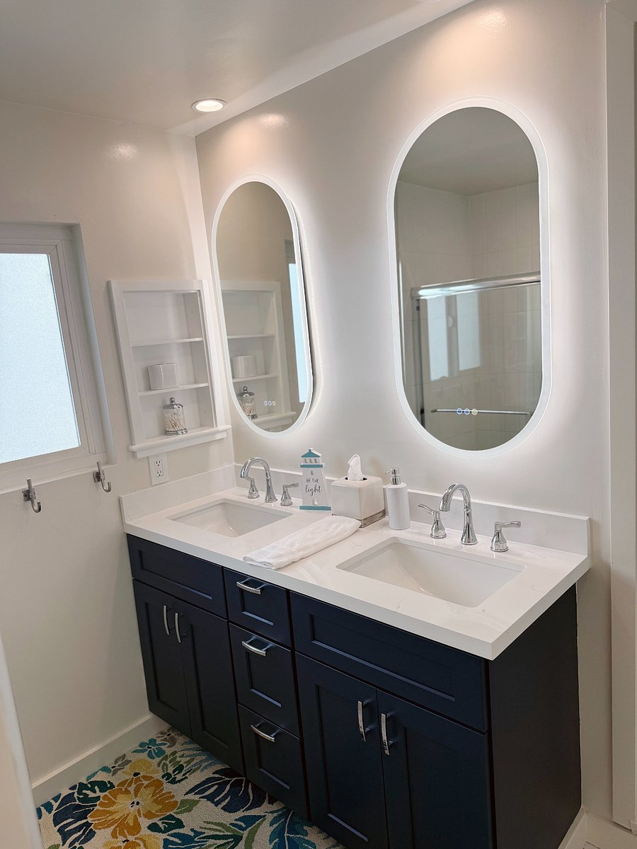 Bathroom with double sink and lighted vanity mirrors.