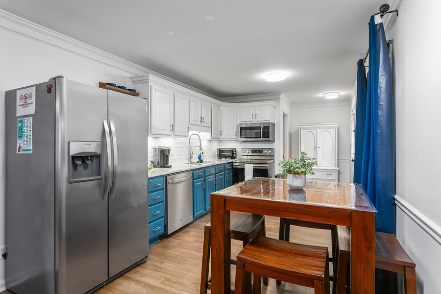 Bar table with stools for extra seating space, Kitchen display with appliances.
