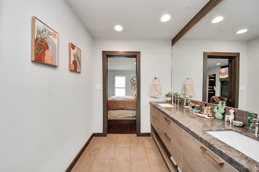 Plenty of counter space for two! This bright primary bathroom offers dual sinks, excellent lighting, fresh towels, and a spacious granite-style countertop.