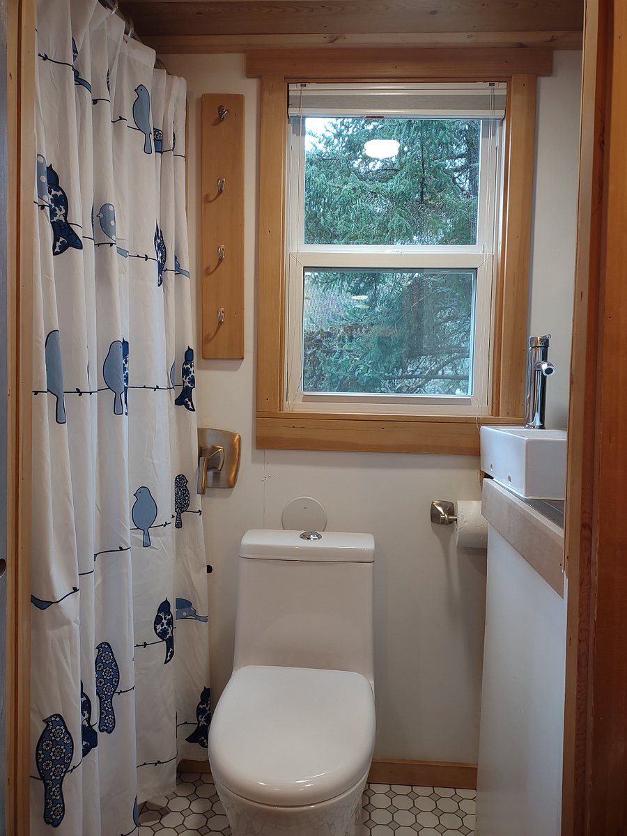 Bathroom with shower, toilet, sink, storage cupboards and view of private garden.