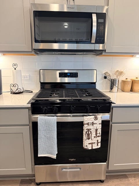Fully equip shared kitchen area with stainless steel appliances, quartz counter top, subway tile backsplash, and a laundry room by the refrigerator. 