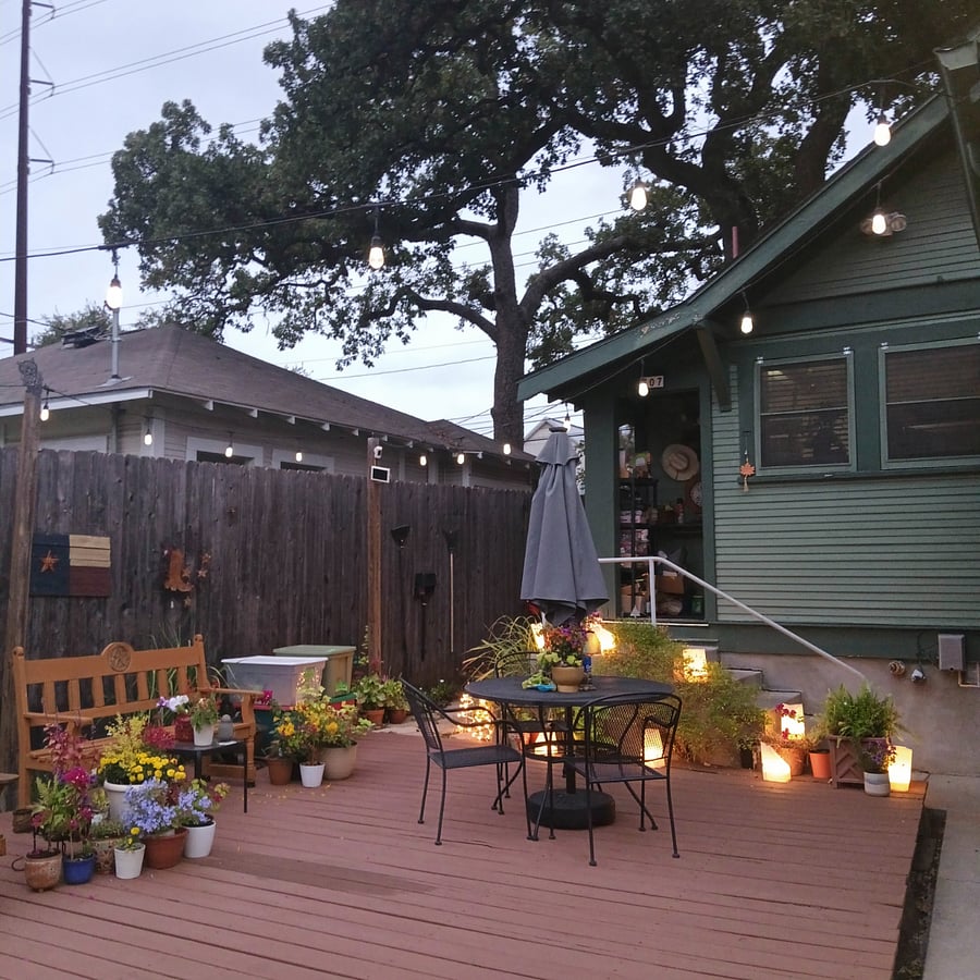 Large back patio deck with ample seating, including patio table with umbrella. Bistro lights add charm.