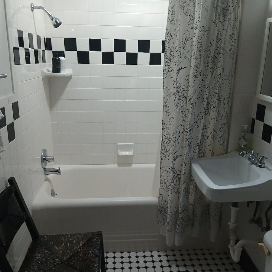 Guest bathroom reflects era with black/white tilework on walls and floor.