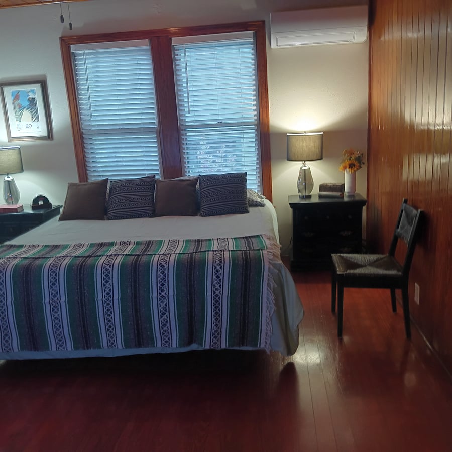 Master bedroom has a king-size bed. Nightstands on either side of the bed have drawers for storage.