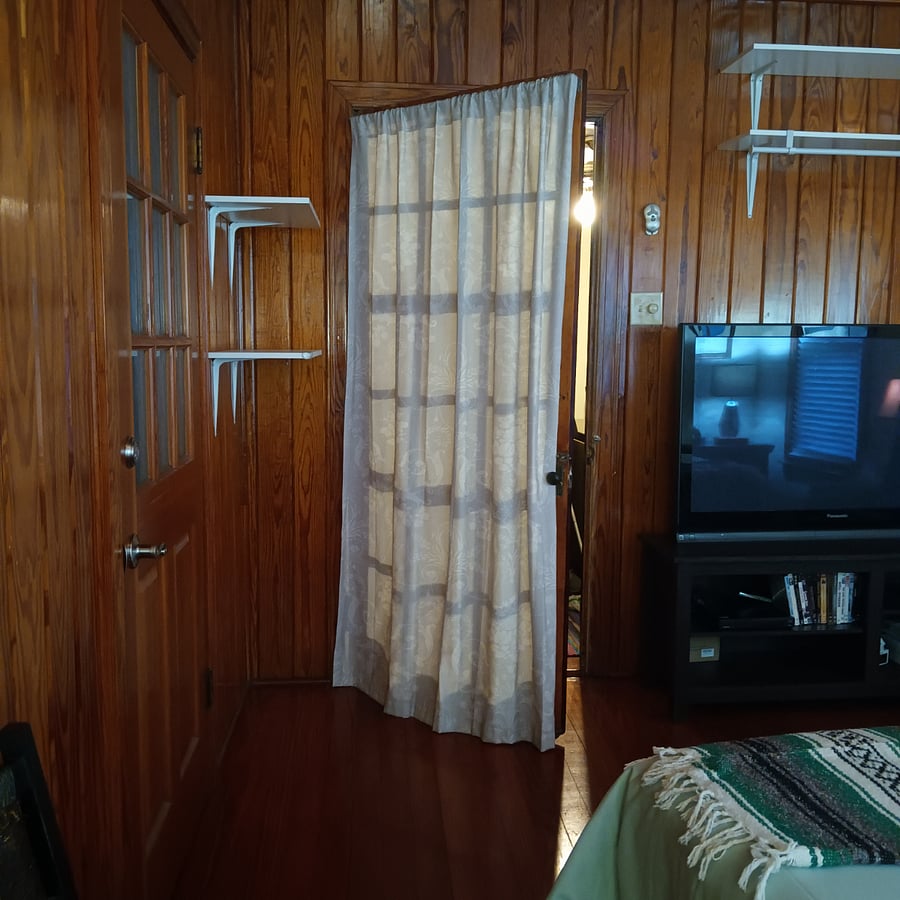 Extra shelving behind bedroom door and above entertainment space.