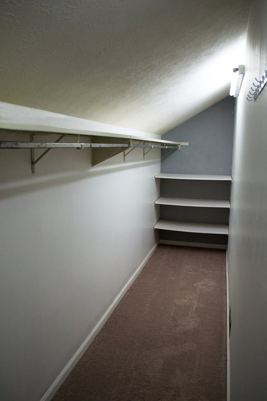 This is the first walk in closet in the primary suite. The closet runs the length of this large room and has shelves at either end for additional storage.