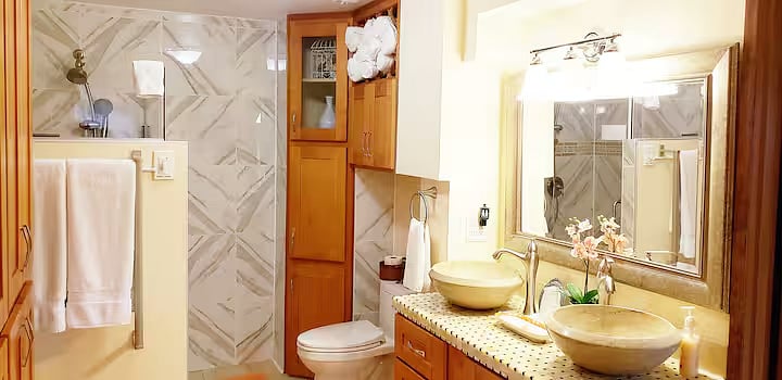 Bathroom: marble double sinks, cupboard, shower to the left.