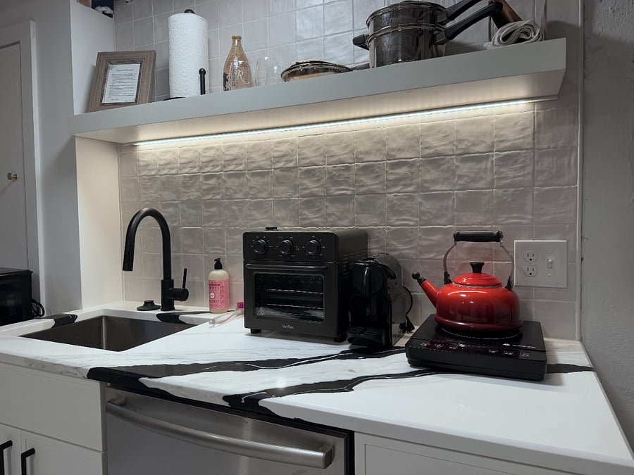 Kitchen includes single induction cooktop burner, Le Creuset tea kettle, Our Place convection oven/air fryer/toaster oven, microwave, full-size European style fridge, full-size dishwasher, garbage disposal