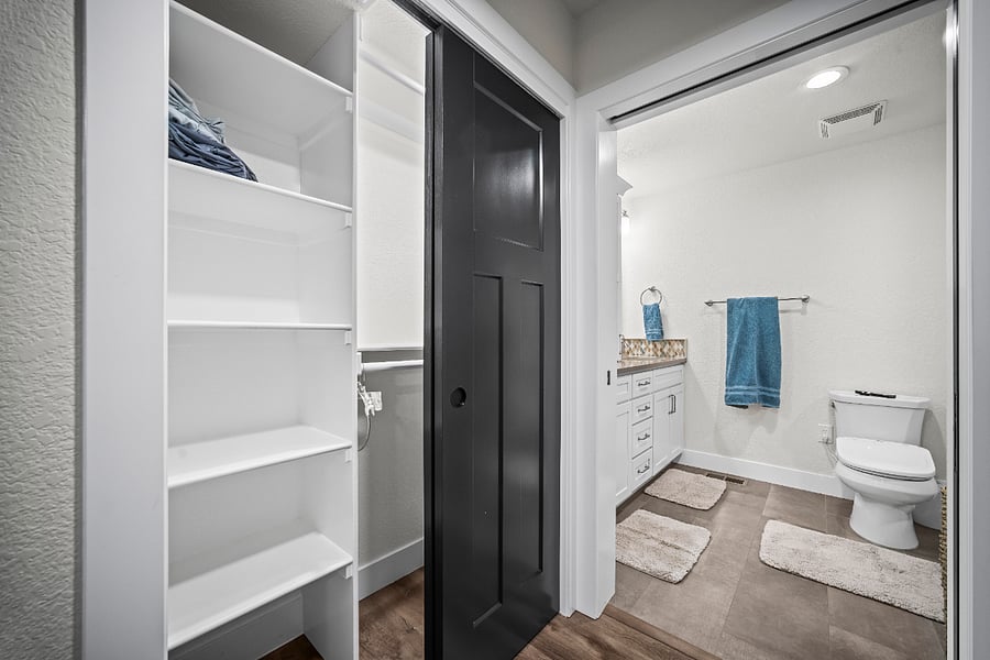 Hallway leading to the bathroom with double designer closets and built-in shelving for extra storage.