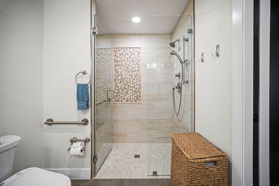 Spacious walk-in shower with modern tile, glass enclosure, updated fixtures, and a built-in grab bar for added stability.