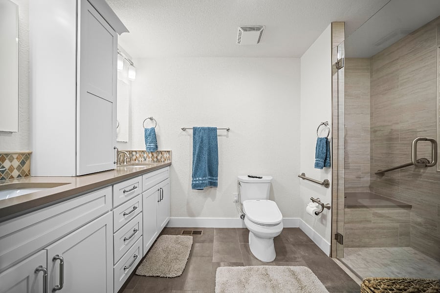 Bright, spacious bathroom with a large vanity, ample storage, and a walk-in shower equipped with a grab bar.